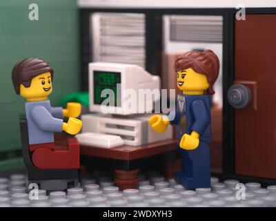 Tambow, Russische Föderation – 21. Januar 2024 Eine Lego-Geschäftsmann-Minifigur sitzt hinter einem Computer und spricht mit einem anderen lego-Geschäftsmann Stockfoto