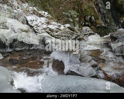Wasserfall, der über eisige Felsen mit Schnee und Eiszapfen stürzt Stockfoto