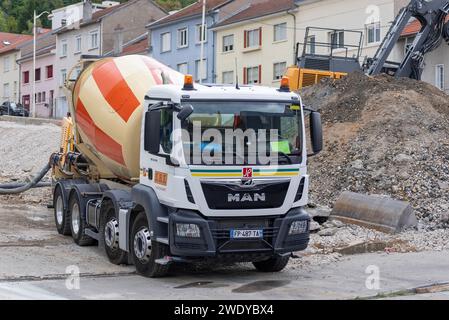 Weiß-gelb-orange Lkw-Mischer MAN TGS 32,430 liefert Beton für Spezialfundamente auf eine Baustelle. Stockfoto