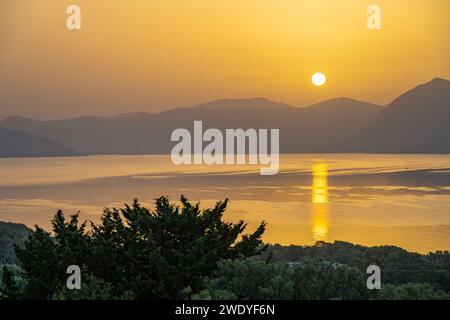 Sonnenaufgang hinter den Bergen des griechischen Festlandes von der Insel Meganisi im Ionischen Meer Stockfoto