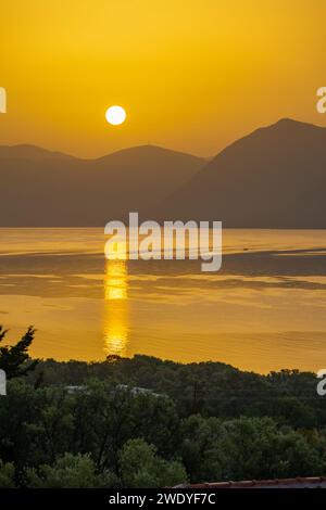 Sonnenaufgang hinter den Bergen des griechischen Festlandes von der Insel Meganisi im Ionischen Meer Stockfoto