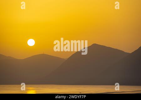 Sonnenaufgang hinter den Bergen des griechischen Festlandes von der Insel Meganisi im Ionischen Meer Stockfoto