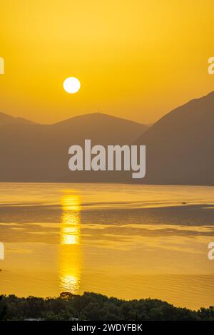 Sonnenaufgang hinter den Bergen des griechischen Festlandes von der Insel Meganisi im Ionischen Meer Stockfoto