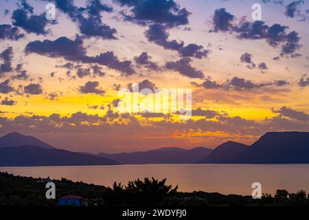 Sonnenaufgang hinter den Bergen des griechischen Festlandes von der Insel Meganisi im Ionischen Meer Stockfoto