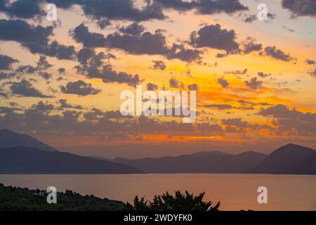 Sonnenaufgang hinter den Bergen des griechischen Festlandes von der Insel Meganisi im Ionischen Meer Stockfoto