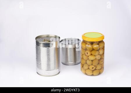 Bügeleisendose mit Tabellenöffner und Oliven im Glasgefäß auf weißem Hintergrund. Stockfoto
