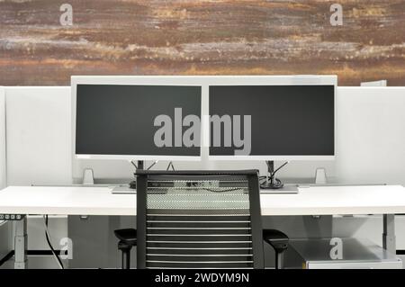 Leerer Büroschreibtisch mit Computermonitoren, Schreibtisch und Stuhl in einer Kabine. Konzeptbild „Arbeiten von zu Hause aus“. Stockfoto