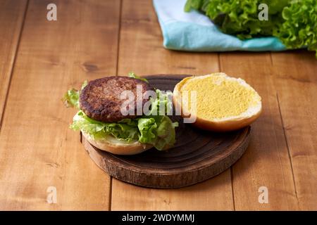 Köstlicher Hamburger mit grünem Salat auf Holztisch. Stockfoto