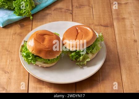 Köstlicher Hamburger mit grünem Salat auf Holztisch. Stockfoto