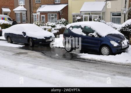 Wasserleck bei eisigem Wetter. Wasserleitungen platzen, was zu einem Überflutungswasser auf der Straße mit Schnee und Eis führt Stockfoto