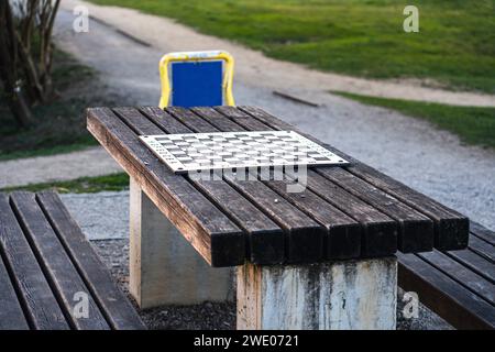 Eine Holzbank in der Mitte des Parks mit einem Schachbrett in der Mitte des Tisches Stockfoto