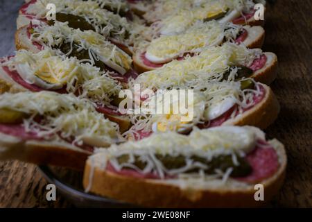 Gewickeltes Sandwich in einer Schüssel, Schinken, Käse, Gurke, Eier auf hölzernem Hintergrund. Stockfoto