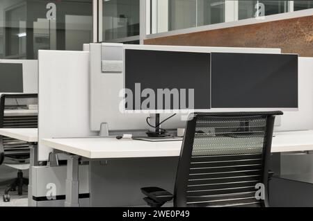 Leerer Büroschreibtisch mit Computermonitoren, Schreibtisch und Stuhl in einer Kabine. Konzeptbild „Arbeiten von zu Hause aus“. Stockfoto