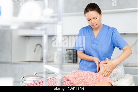 Erfahrener Arzt, der eine Gesichtsmassage an einen Reifen Patienten durchführt Stockfoto