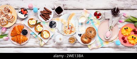 Osterfrühstück oder Brunch-Tisch. Blick von oben auf weißem Holzbanner. Hasenpfannkuchen, Eiernester, Hühnerfrüchte und eine Auswahl an Säften Stockfoto