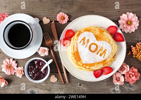 Pfannkuchen mit Herzform und MAMA-Buchstaben. Frühstückskonzept zum Muttertag. Tischszene mit Blick von oben mit rustikalem Holzhintergrund. Stockfoto