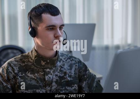 Militärdienst. Junger Soldat in Kopfhörern, der im Büro arbeitet Stockfoto