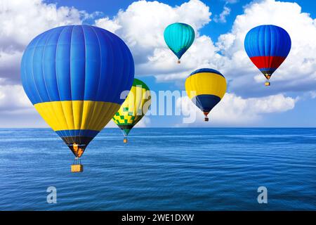 Helle Heißluftballons fliegen über blaues Meer Stockfoto