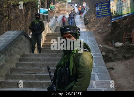 22. Januar 2024, Srinagar Kashmir, Indien: Ein indischer paramilitärischer Soldat steht auf der Wache, als hinduistische Gläubige bei der Einweihung des neu erbauten Lord RAM Tempels in Ayodhya in Srinagar an den Gebeten teilnehmen. Der Ayodhya RAM Tempel wird mit Tausenden von Würdenträgern eingeweiht. Der indische Premierminister Narendra Modi führt zusammen mit einem Team von Priestern die wichtigsten Rituale des „Pran pratishtha“ durch. In der Tempelstadt wurde die Sicherheit verstärkt, und das Personal der Rapid Action Force wurde an strategischen Orten eingesetzt. Am 22. Januar 2024 Wurde Srinagar Kashmi Stockfoto