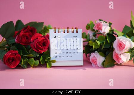 Schreibtischkalender für Februar 2024 auf rosafarbenem Hintergrund mit Rosen. Stockfoto