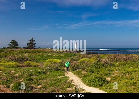 Gewundener Wanderweg durch Strauchvegetation mit Port Fairy Lighthouse im Hintergrund auf Griffiths Island of Port Fairy in Victoria, Australien. Stockfoto