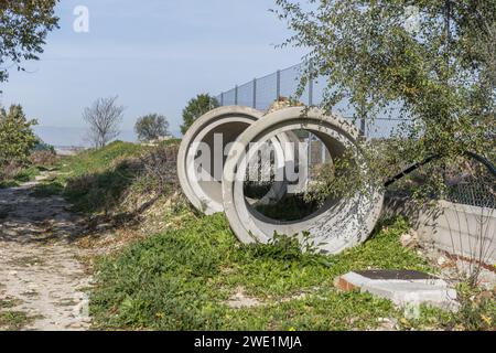 Große Zementrohre wurden in der Mitte des Feldes neben einem Zaun gelassen Stockfoto