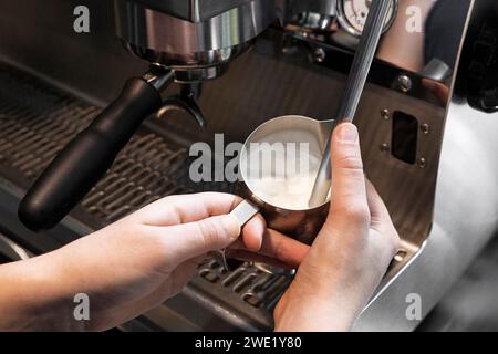 Aufschäumen von Milch in einem Edelstahlbecher mit Espressomaschine. Stockfoto