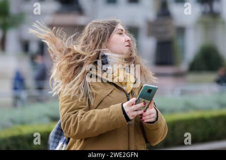 London, Großbritannien. Januar 2024. Eine Frau in Westminster, Central London, hat starke Winde, verursacht durch Sturm Isha. Sturm Isha führt zu Reisestörungen und Trümmer fallen von Gebäuden. Quelle: SOPA Images Limited/Alamy Live News Stockfoto