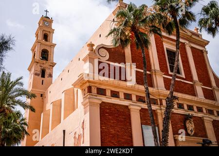 Ein fesselndes Reisebild der antiken St. Peter's Church mit ihrem berühmten Uhrenturm, eingerahmt von Palmen in Jaffa, Israel. Stockfoto