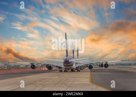 Riesige Flugzeuge Reihen sich in einer Reihe an, Blick von hinten auf die Flügel und den Schwanz während des hellen Sonnenaufgangs eines wunderschönen Himmels Stockfoto