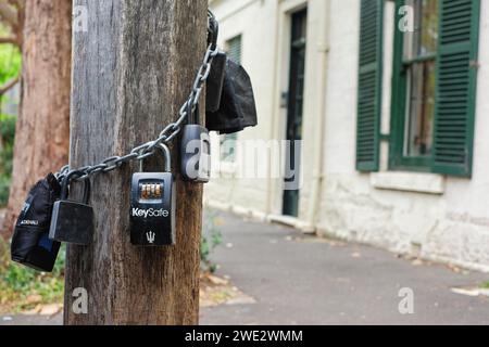 Eine innerstädtische Straße mit Terrassenhäusern, Schlüsselschließfächer hängen an einer Kette um einen hölzernen Lichtmast für die Vermietung von Airbnb-Kurzzeitwohnungen in Sydney Stockfoto