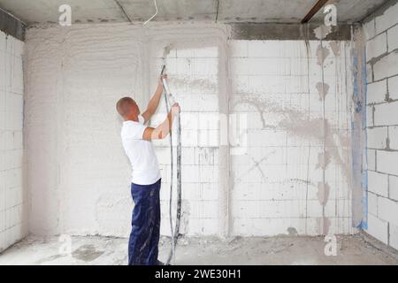Arbeiter-Gipser verputzt Hauswände, veredelt Wände mit Sprühputzmaschine. Estrich an der Wand. Verputz W Stockfoto