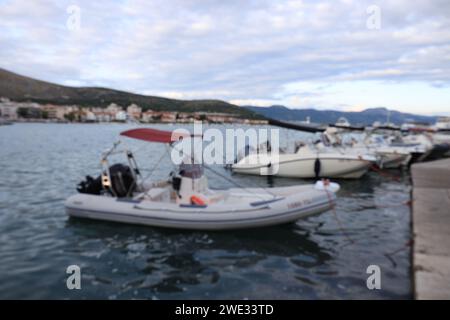 Verschwommener Blick auf vertäute Boote, Stadt, Berge und Meer an bewölkten Tagen Stockfoto