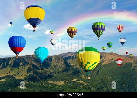 Helle Heißluftballons fliegen in den Himmel mit Regenbogen über den Berg Stockfoto