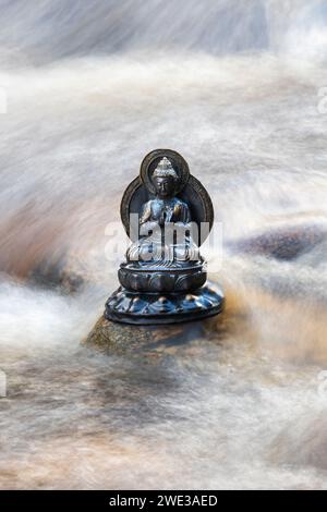 Buddha-Statue in den schnell fließenden Gewässern des Flusses Findhorn. Morayshire, Schottland Stockfoto