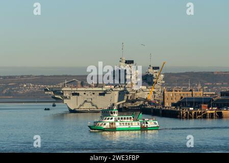 Die Gosport Fähre überquert den Hafen von Portsmouth vor den Flugzeugträgern der Navy, der HMS Queen Elizabeth und Prince of Wales. Januar 2024 Stockfoto