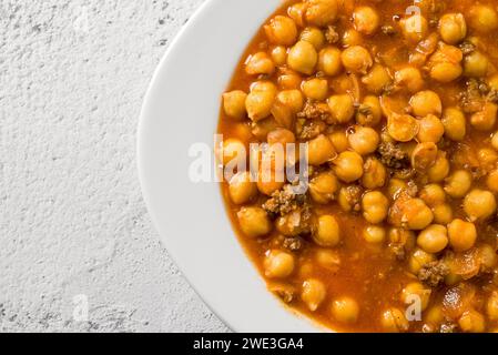 Kichererbseneintopf mit Hackfleisch auf einem weißen Porzellanteller auf einem Steintisch Stockfoto