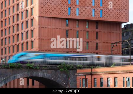 Ein Hochgeschwindigkeitszug, der auf einer elektrifizierten Strecke über einem Viadukt aus Backsteinen neben dem Maldron Hotel in Manchester, Großbritannien fährt Stockfoto