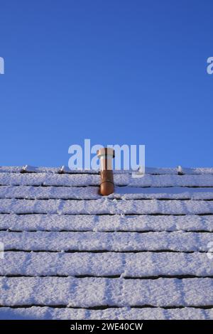 Schornstein und schneebedecktes Dach eines Bauernhauses vor blauem Himmel, Szigethalom, Ungarn Stockfoto