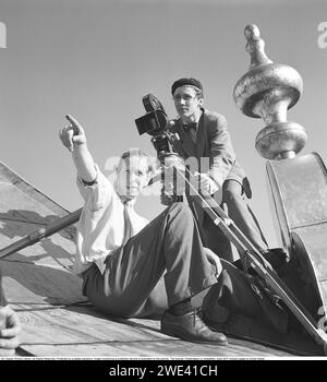 Kühne Dreharbeiten auf dem Dach des Stadhustornet in Stockholm in den 1940er Jahren Zwei junge Männer mit einer Filmkamera sitzen auf dem Kupferdach des Rathausturms. Die verwendete leichte und kleinere Filmkamera ist auf einem Stativ montiert. Der Mann hinter der Kamera in einer Baskenmütze ist der Kameramann Kurt Jonsson (1921–1958), der hauptsächlich in der Filmfirma Sandrews tätig ist. Regisseur per Gunvall wird gezeigt. Das Jahr ist 1946. Das Foto, das im Zusammenhang mit der Aufnahme des Kurzfilms und Dokumentarfilms Hu! Aufgenommen wurde Ein kurzer Filmstreifen unter gesunden Jungen und Jobs mit Risiken, der am 15. Februar 1947 in Schweden uraufgeführt wurde. Stockfoto