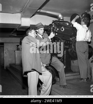 Hasse Ekman. 1915-2004. Schwedischer Schauspieler und Regisseur. Hier mit dem Filmproduzenten Lorens Marmstedt. 1908-1966 in einem Kinovorstellungsraum. Sie stehen im Projektorraum eines Kinos und schauen sich den Filmstreifen einer Filmrolle genau an, der im Projektor gezeigt werden soll. 1952. Kristoffersson Ref. BG91-4 Stockfoto