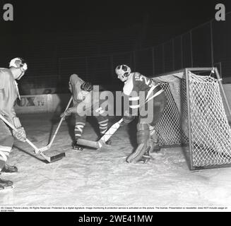 Eishockey in den 1950ern Ein Torhüter und zwei Spieler auf der Eishockeybahn. 1959. Kristoffersson Ref. CL20-2 Stockfoto