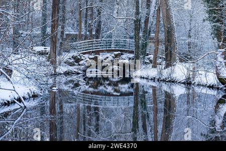 Kleine Brücke über einen Bach im Parc de Géresme (Geresme Park) unter Schnee in Crépy-en-Valois, Frankreich. Winterliche Schneelandschaft in Crepy-en-Valois. Stockfoto