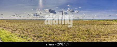 Panoramabild eines Windparks mit einem Kohlekraftwerk im Hintergrund während des Tages Stockfoto