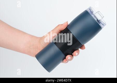 Blauer Metallbecher in der Hand Seitenansicht isoliert auf weißem Studiohintergrund Stockfoto