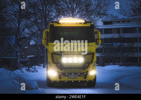 Brillante Scheinwerfer und Zusatzleuchten eines neuen gelben Volvo FH Kipper-Lkw, der in blauer Winternacht Schnee transportiert. Salo, Finnland. Januar 2024. Stockfoto