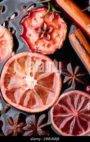 Glühwein mit Scheiben trockener Orange, Apfel, Zimt, Sternanis, Rosmarin und Preiselbeeren aus nächster Nähe. Lebensmittelfotografie Stockfoto