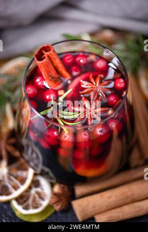 Ein Glas Glühwein mit Orangenscheiben, Zimtstab, Sternanis, Rosmarin und Preiselbeeren aus nächster Nähe. Lebensmittelfotografie Stockfoto