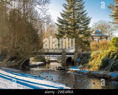 Die Brücke überquert den Fluss Wye und schlängelt sich durch die schneebedeckten Pavilion Gardens in Buxton. Derbyshire. Stockfoto