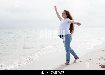 Schwangere Frau genießt den Ozean. Schwangere Frau am Strand. Glückliche gesunde Schwangerschaft. Wellness-Konzept Stockfoto